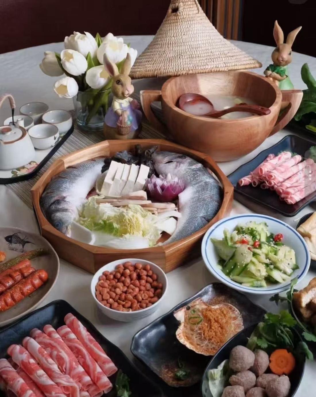 整桌菜色：鮮魚木盤、羊肉捲、花生、涼拌黃瓜、貢丸與茶具